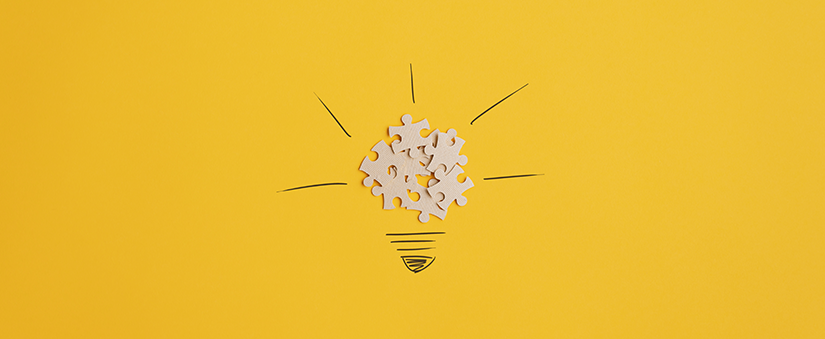 Metas SMART: peças de quebra-cabeça se juntam para formar uma lâmpada branca num fundo amarelo