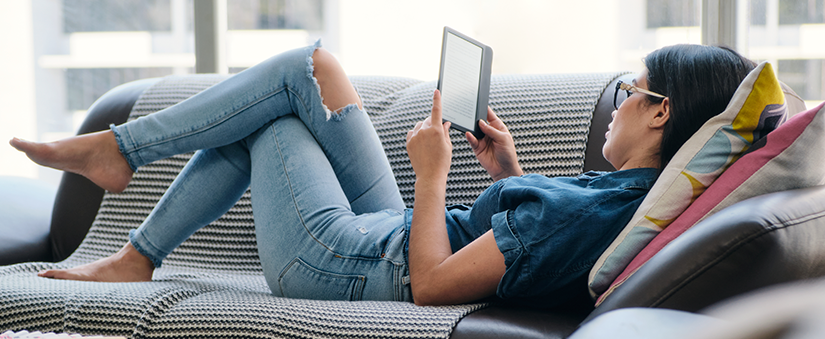 Site para incorporadoras: mulher utiliza leitor digital deitada no sofá