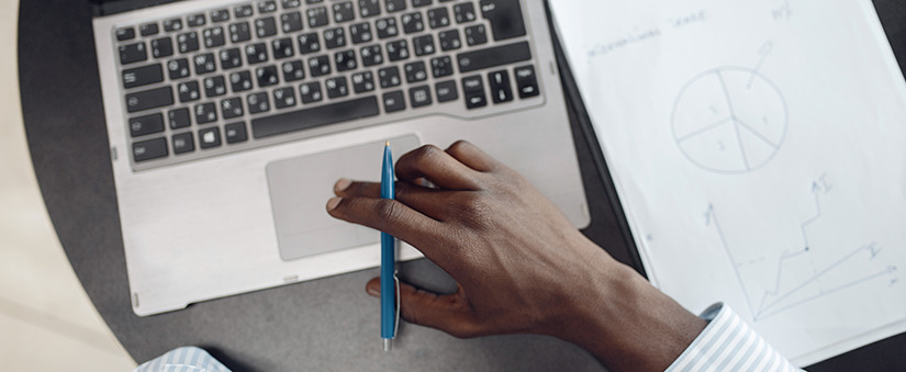 Mão segura caneta e mexe em cursor de notebook