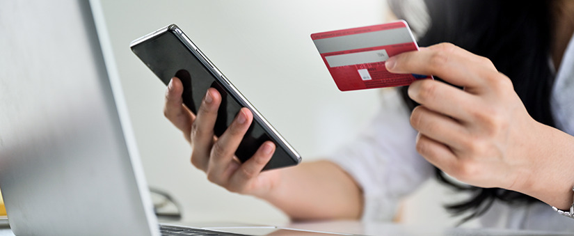 Análise de crédito: mulher olhando cartão de crédito e segurando celular.