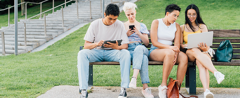 omnicanal : Grupo de jovens num banco ao ar livre usando celulares e notebooks