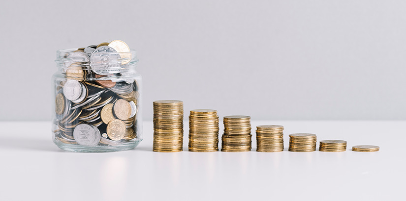 redução de custos: imagem de um pote de vidro com muitas moedas e, ao lado, algumas moedas empilhadas e enfileiradas.