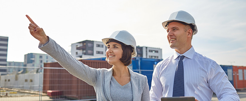 tecnologia na construção civil: um homem e uma mulher usando capacete olham na mesma direção.