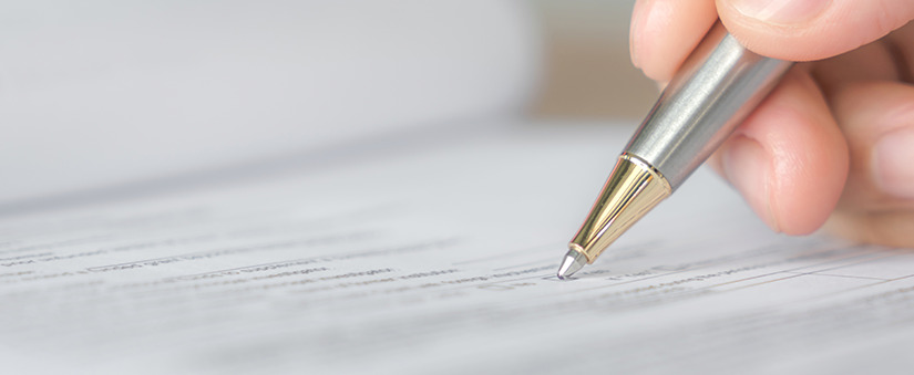 financiamento imobiliário: close numa mão segurando uma caneta em cima de um papel.