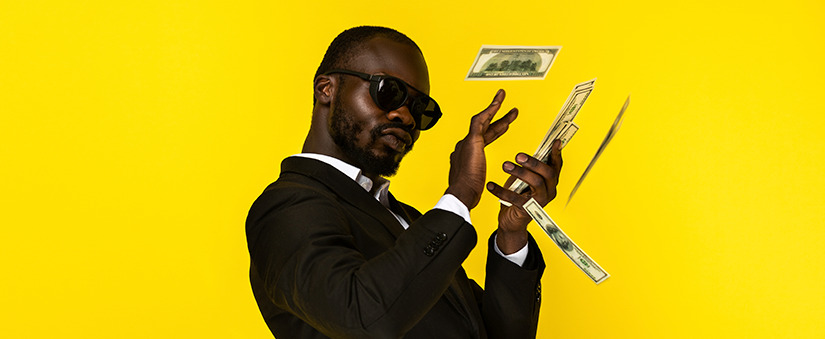 Fundo amarelo e homem de terno e óculos preto segurando cédulas de dinheiro.
