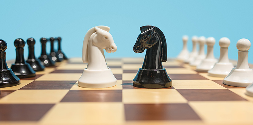 Técnicas de vendas: tabuleiro de xadrez com foco em duas peças de cavalo frente a frente.