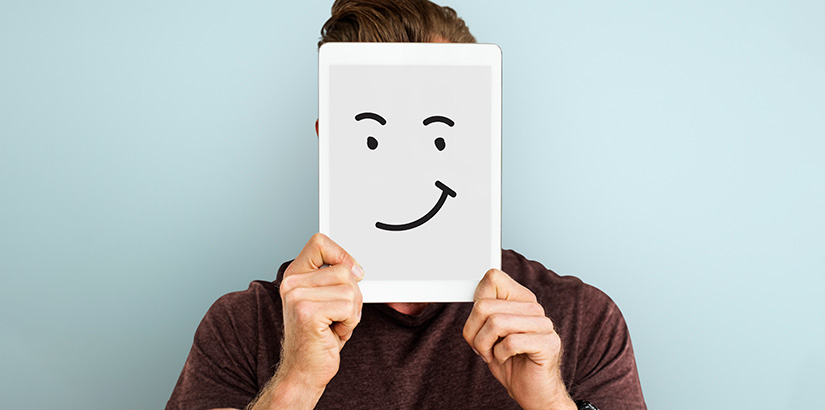 anonimização de dados: imagem de uma pessoa segurando um tablet com um rosto feliz à frente do próprio rosto.