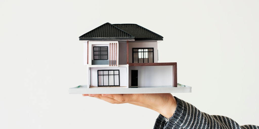 FGTS para compra de imóvel: imagem de uma mão segurando uma miniatura de casa.