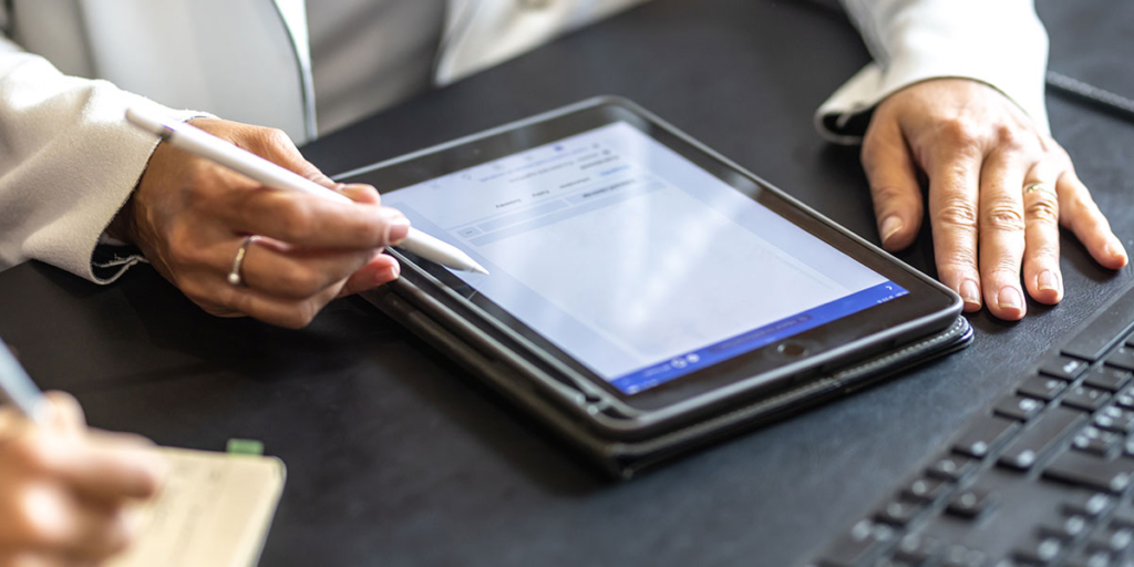 assinatura eletrônica: close em mãos manuseando um tablet em cima de uma mesa.