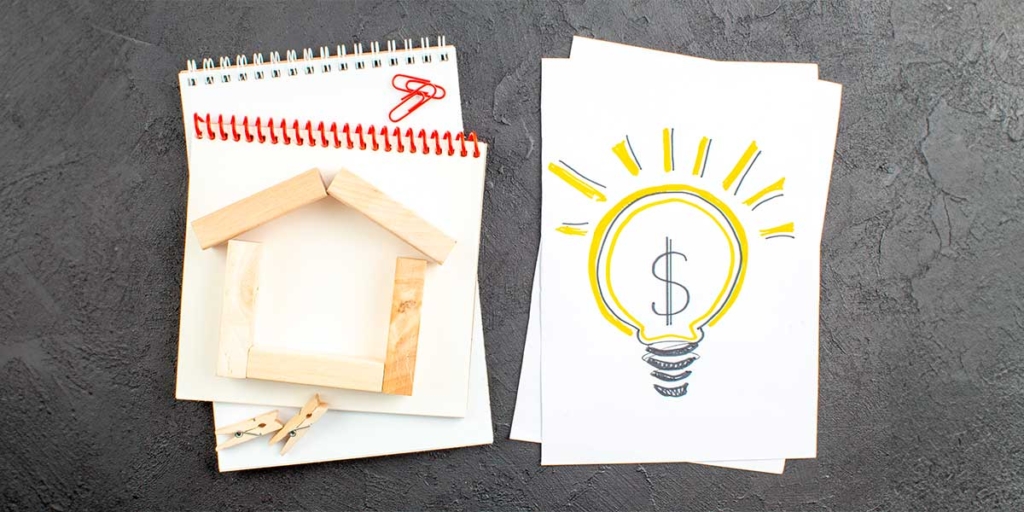 compra de imóveis: imagem de dois cadernos vistos de cima com ilustrações de uma lâmpada e uma casa de madeira.
