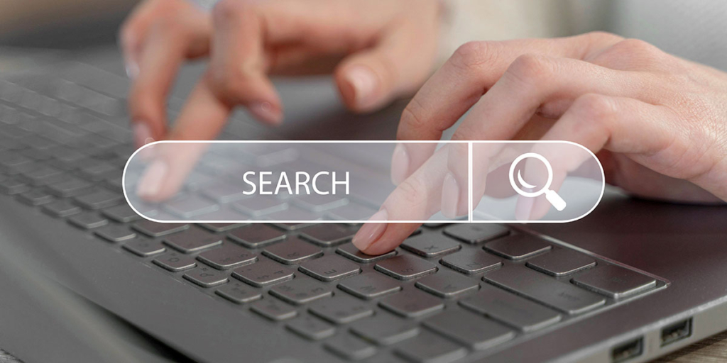 Estratégias de marketing digital: close em mãos digitando num teclado e uma ilustração de caixa de busca na frente.