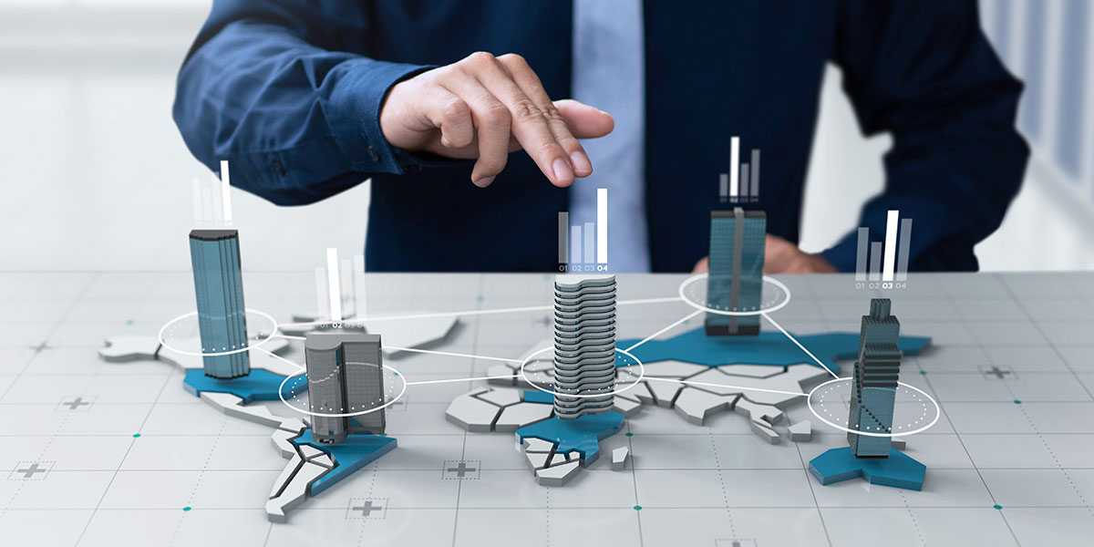 Inteligencia-de-mercado-imobiliario: imagem das mãos de um homem numa maquete com vários edifícios.