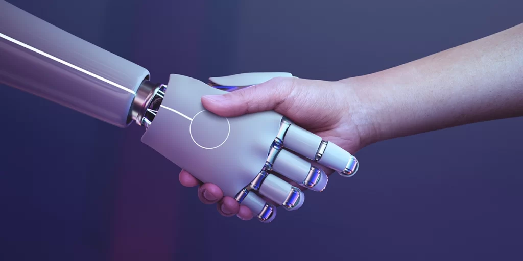 O que é um assistente virtual: imagem da mão de uma pessoa apertando a mão de um robô.