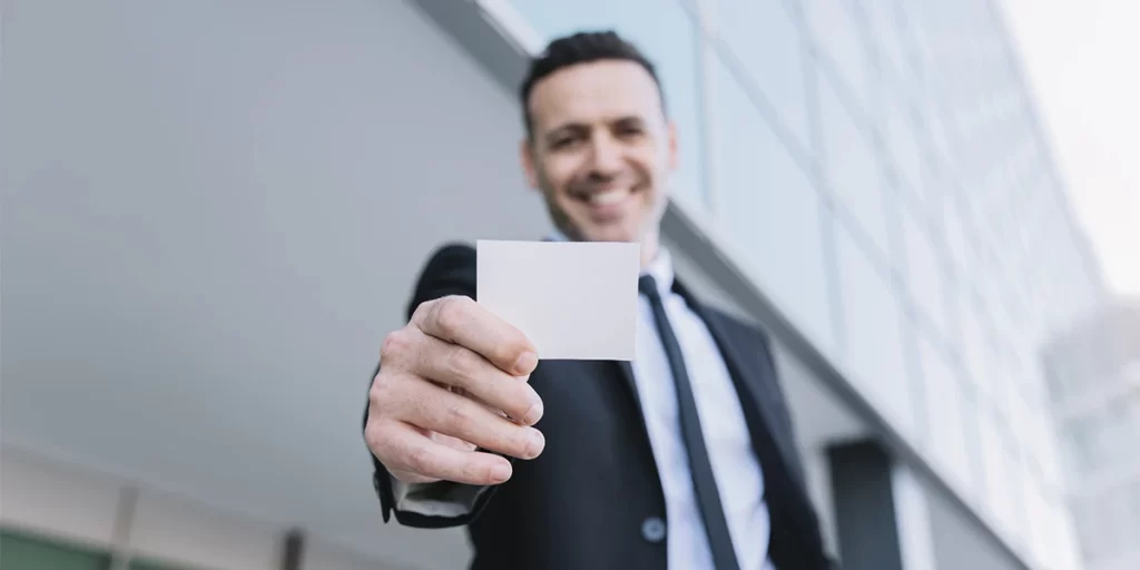 Carteira de corretor de imóveis: imagem de um homem sorrindo, segurando uma carteira próxima a câmera.