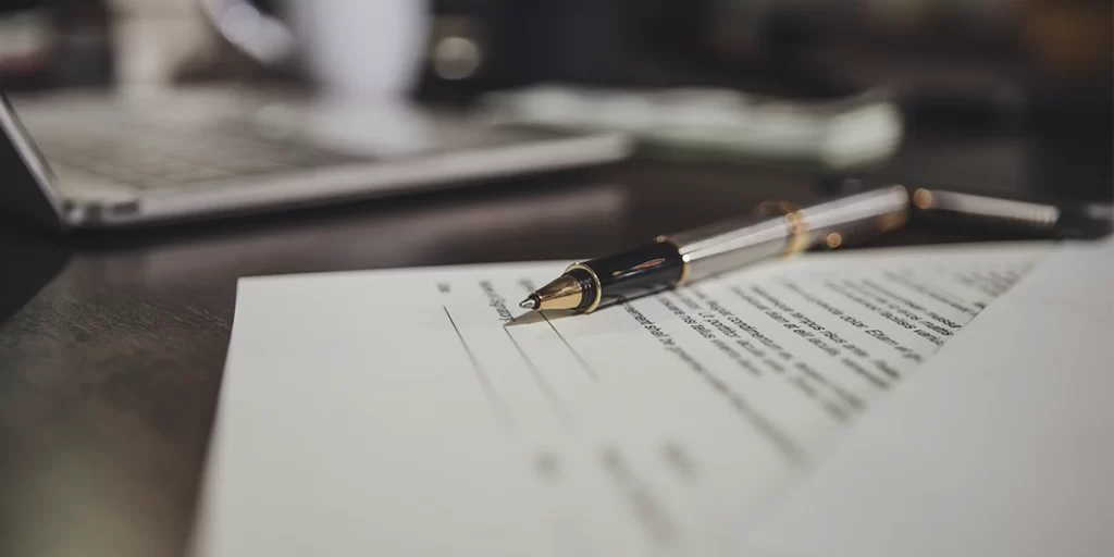 Código de Ética do corretor de imóveis: close de um papel com um contrato e uma caneta em destaque perto do campo de assinatura.