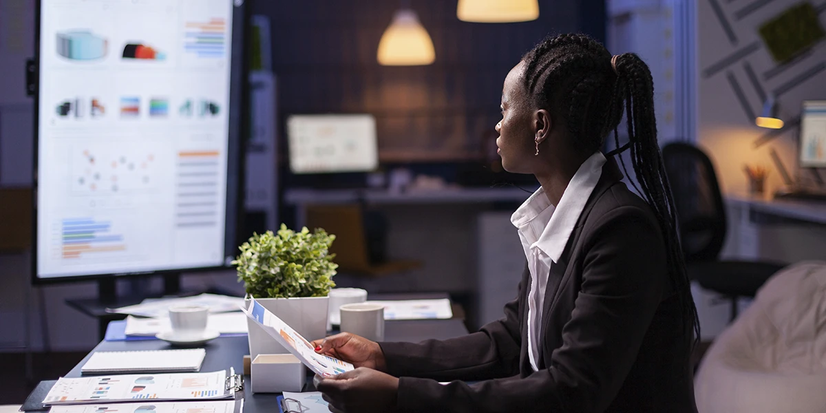 Growth Marketing: imagem de uma mulher sentada em frente a uma mesa num escritório. À sua frente uma tela com vários gráficos.