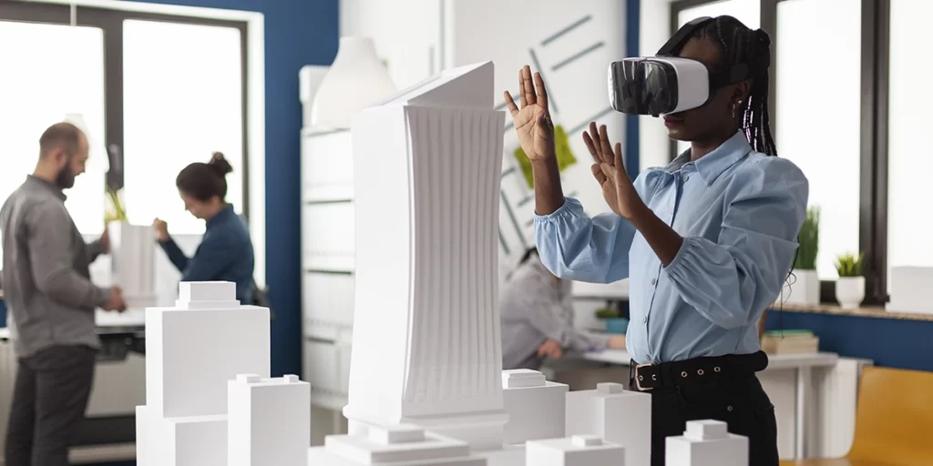 Stand de Vendas de imóveis: imagem de um escritório. Em destaque, no espaço, uma maquete branca de um empreendimento. Ao lado da maquete uma mulher usa um óculos de VR e movimenta as mãos.