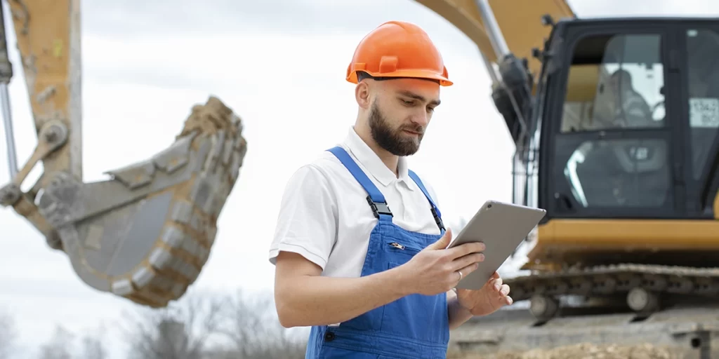 Gestão de Resíduos na Construção Civil: imagem de um homem num canteiro de obras segurando um tablet.