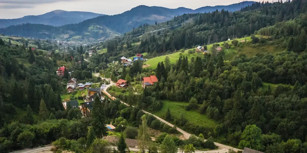 lançamento de loteamento: A imagem mostra uma vista aérea de uma área residencial com uma arquitetura que parece ser europeia. Há uma variedade de edifícios de arquitetura tradicional, com telhas de telhas e telhas de telhas, algumas com telhas de telhas e telhas de telhas. As casas estão dispostas em uma ordem desordenada, com caminhos e ruas que se cruzam e se bifurcam. Há uma quantidade significativa de vegetação, incluindo árvores e grama, que parecem ser bem cuidadas e que contornam os edifícios, criando um contraste entre o verde da natureza e o material do edifício. A imagem é tirada de cima, o que permite uma visão panorâmica da área, e parece ser uma foto de um dia claro, com luz natural que ilumina as casas e a vegetação.