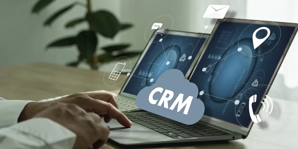 CRM para incorporadoras: close nas mãos de uma pessoa digitando num teclado de notebook. Da tela sai um ícone com a sigla CRM.