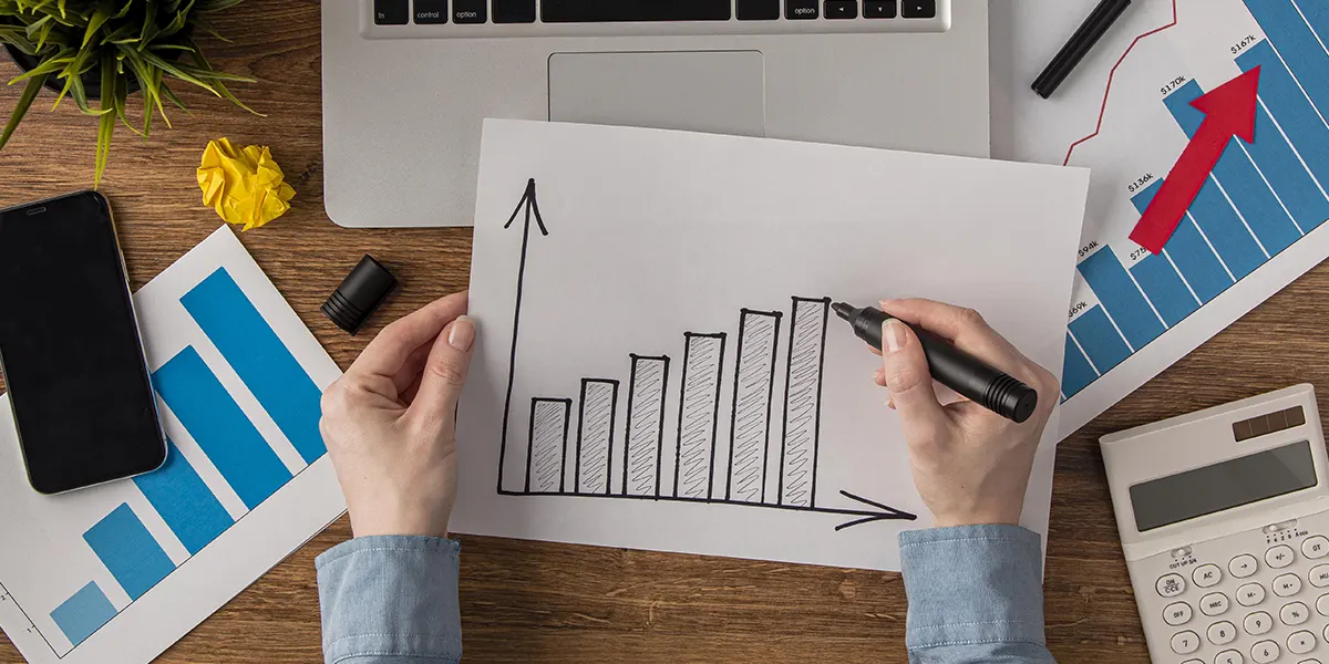 Relatórios de vendas de incorporadoras: a imagem apresenta a mão de uma pessoa desenhando um gráfico em um papel.
