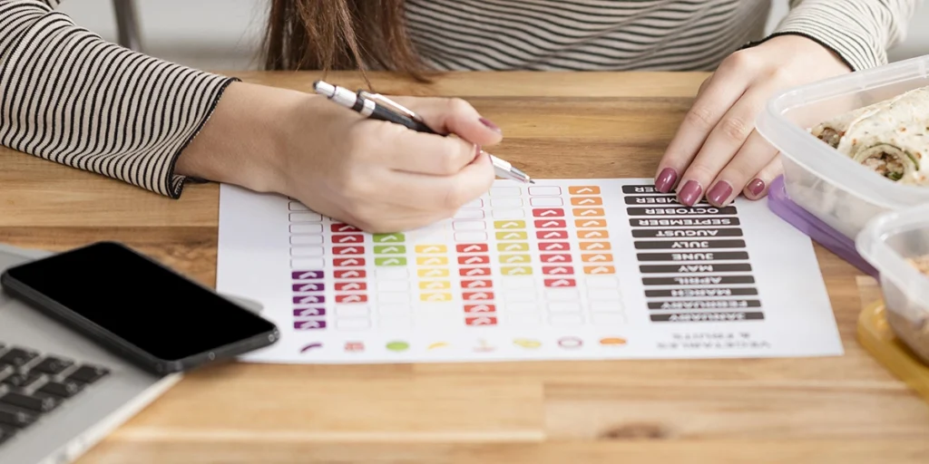 cronograma financeiro: imagem das mãos de uma pessoa diante de uma mesa de madeira preenchendo um papel com alguns checklists.