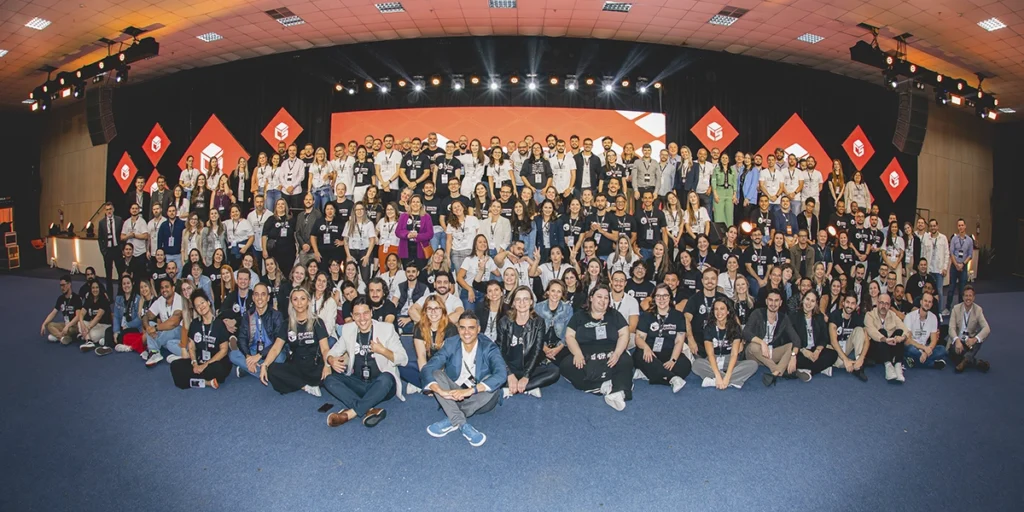 O que é o Construsummit: a imagem  dezenas de pessoas posando para a foto, todas elas com crachás, camisas padronizadas e semblante feliz. 