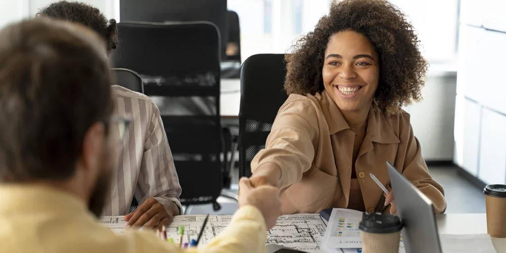 Atendimento de leads: na imagem, uma mulher cumprimenta um homem com um aperto de mão. 