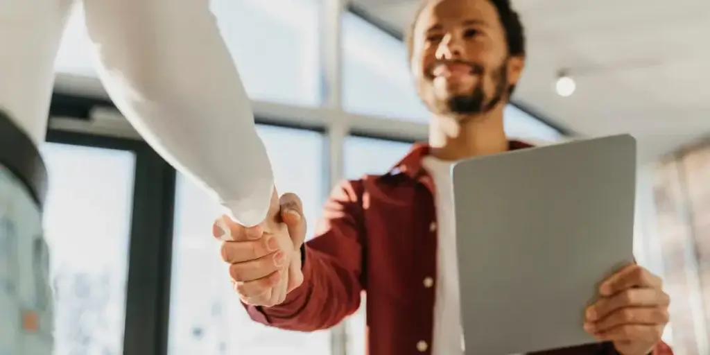 vender com CRM vender com CRM: imagem de duas pessoas apertando as mãos num escritório.