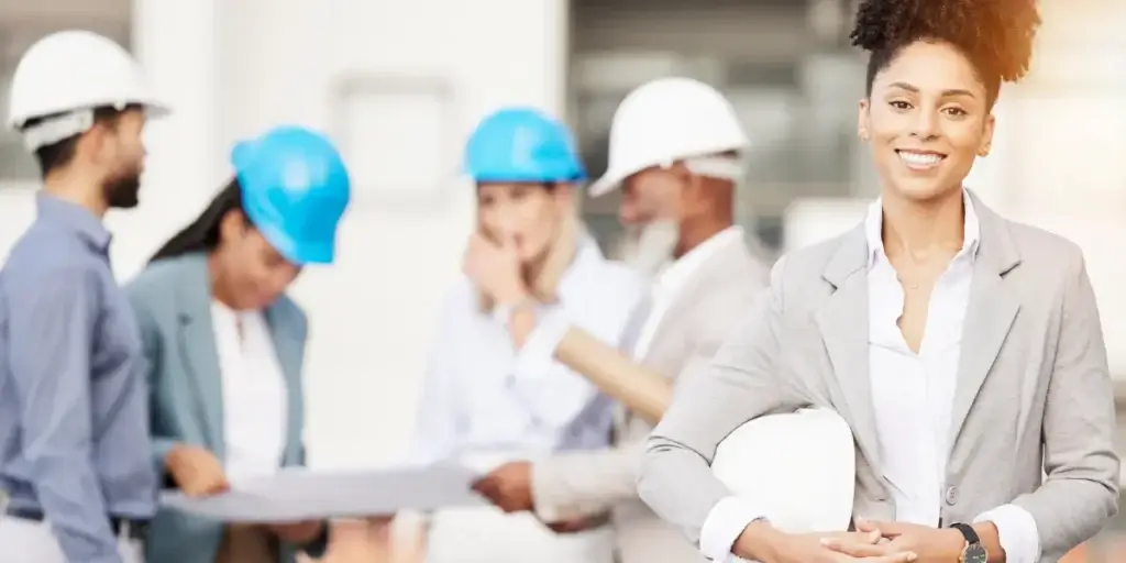 Qualidade na construção civil Qualidade na construção civil: imagem mostra pessoas reunidas, usando capacete de proteção próprio para obra, segurando um projeto de papel. Há frente tem uma mulher sorrindo, segurando um capacete de obra.
