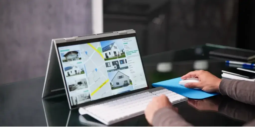 conteúdo para o mercado imobiliário conteúdo para o mercado imobiliário: imagem mostra as mãos de uma pessoa mexendo em uma teclado e um mouse de computador. Na tela há a imagem de casas e um mapa.