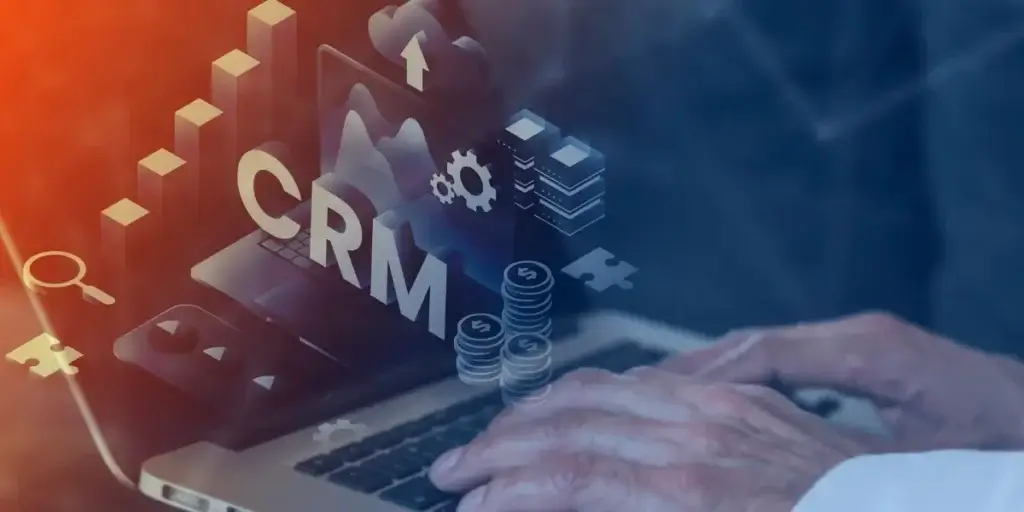 Qual é o CRM mais completo: imagem de mãos digitando num notebook. Na frente da imagem, em destaque, a sigla CRM.
