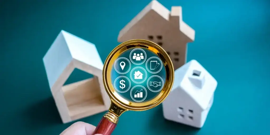 o que é CRM imobiliário o que é CRM imobiliário: A composição da imagem apresenta uma lupa dourada centralizada sobre vários modelos de casas de madeira e de gesso. No centro da lupa há ícones relacionados a imóveis sobrepostos.