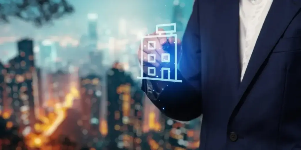 Estratégia de gestão de lançamentos imobiliários Estratégia de gestão de lançamentos imobiliários: Um homem de terno interage com uma representação digital de um edifício contra um fundo urbano desfocado de arranha-céus iluminados à noite.