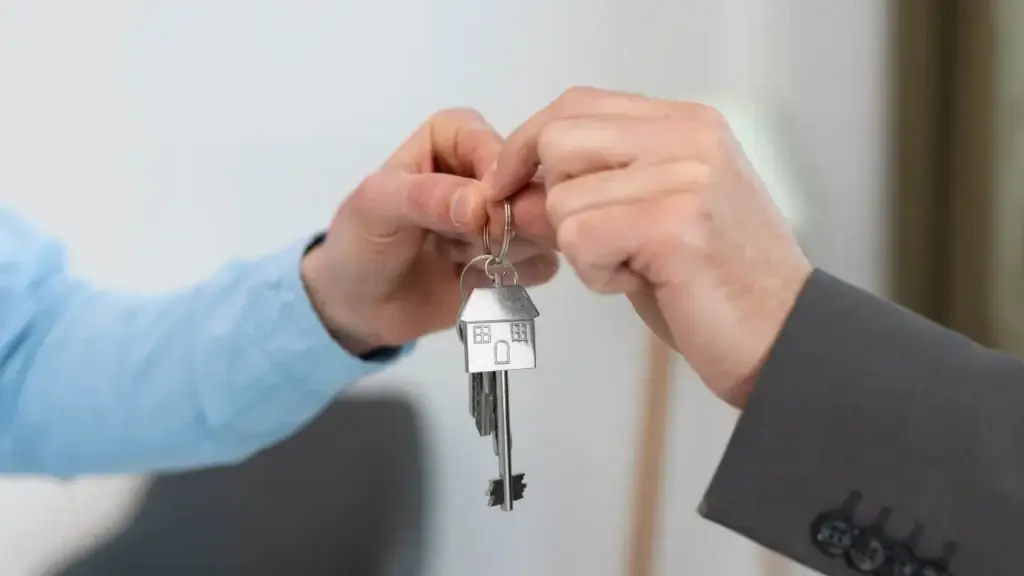 lead scoring imobiliário lead scoring imobiliário: imagem mostra duas mãos masculinas segurando uma chave com um chaveiro em formato de casa.